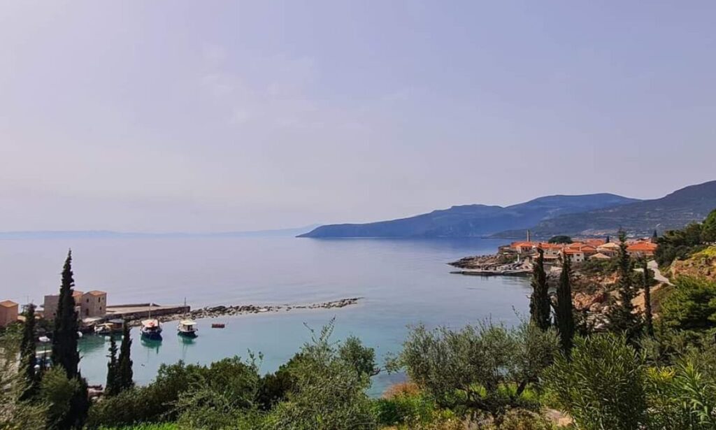 Stunning view of the Kardamili coastline, with boats docked by the shore, surrounded by olive groves and scenic mountains.