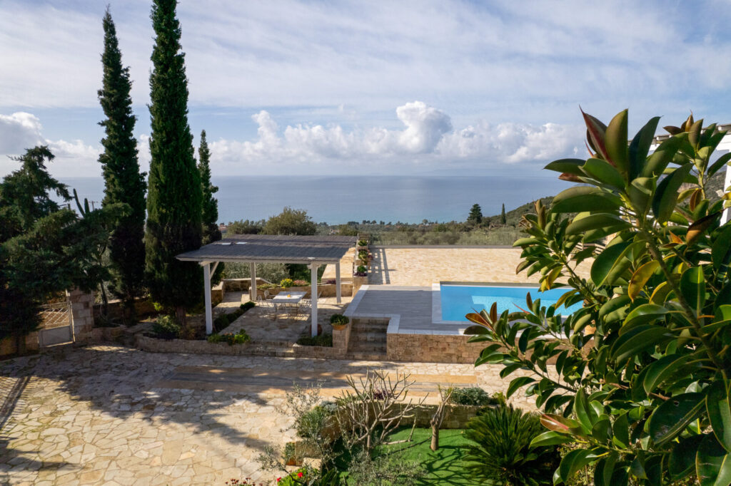 Stone terrace with pool and pergola overlooking the sea at Villa Leonidas in Kardamili, Greece.