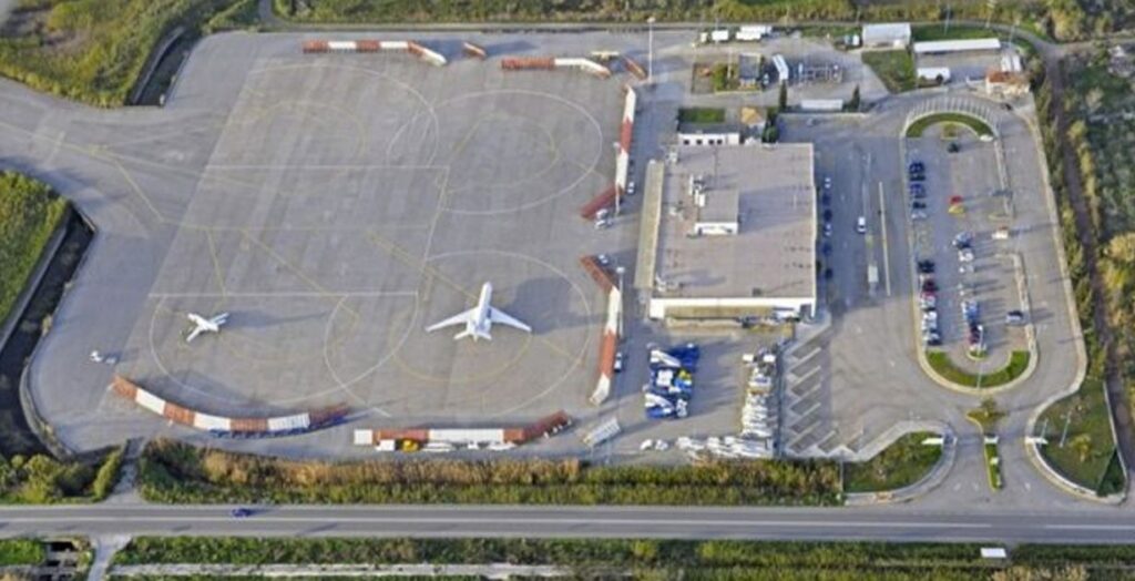 Aerial view of Kalamata International Airport showing the runway, terminal building, and parked airplanes