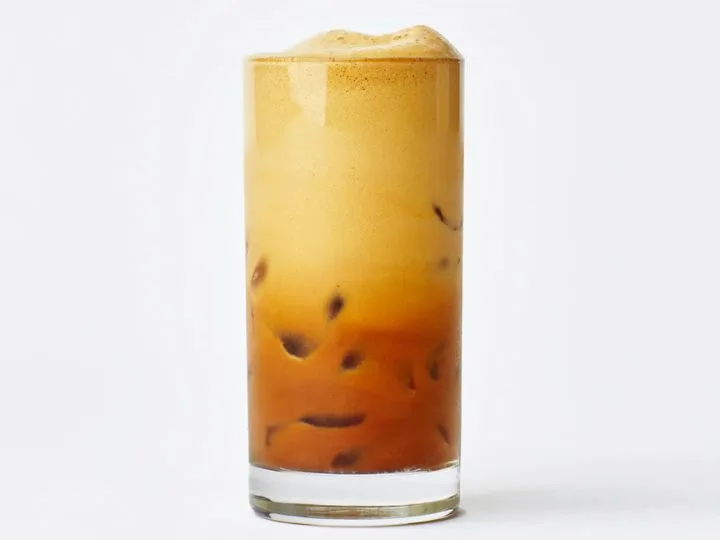 Close-up of a classic Greek frappé iced coffee with foam and ice in a clear glass