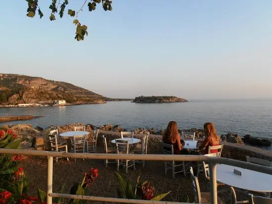 Two women enjoying dinner at Lela’s Taverna with a sea view at sunset in Kardamili, Greece