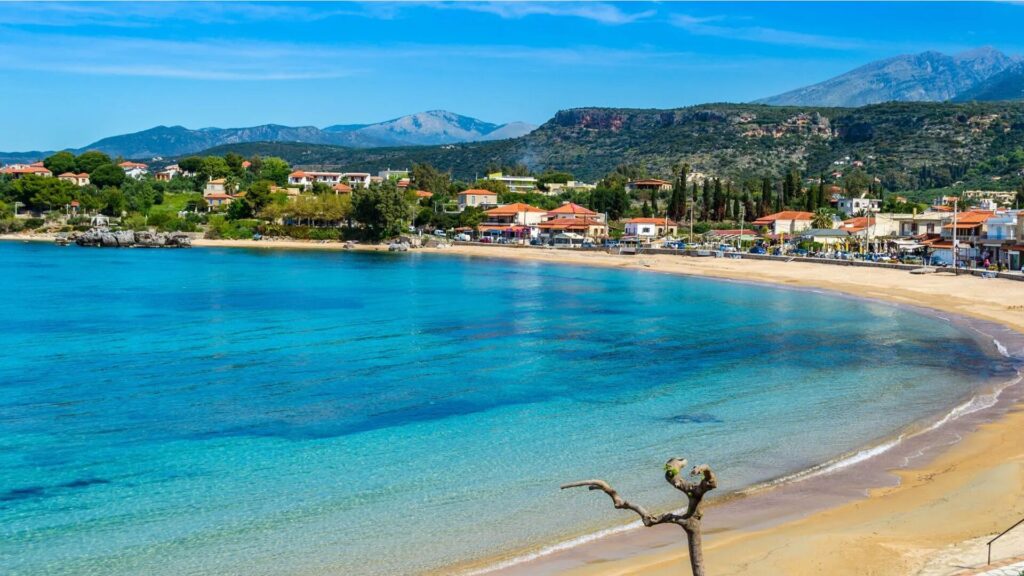 Stoupa Beach in the Peloponnese, Greece, with turquoise waters, sandy shoreline, and scenic mountain backdrop.