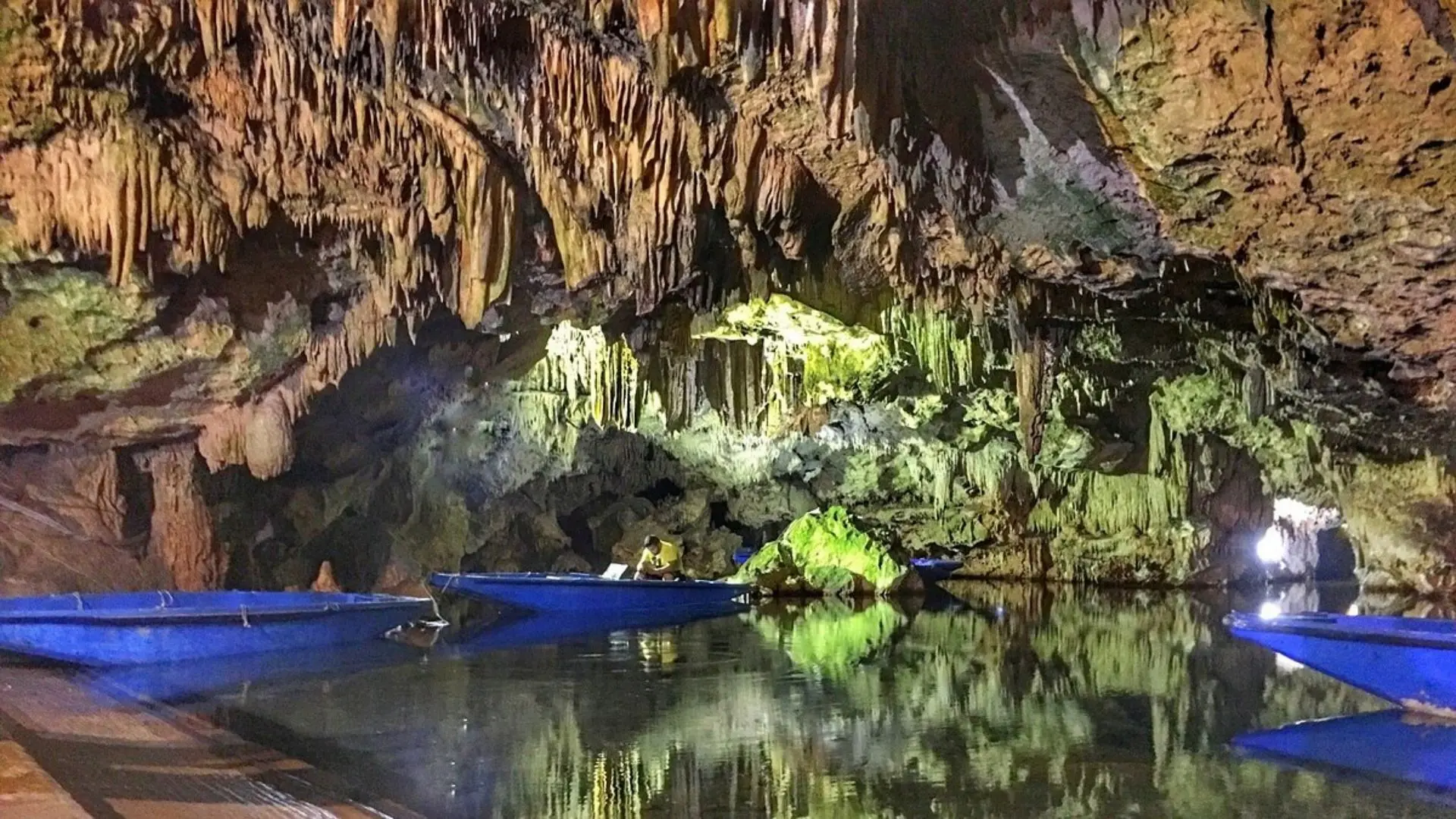 Boat tour inside the illuminated Caves of Diros with dramatic stalactites and underground lake in Peloponnese, Greece