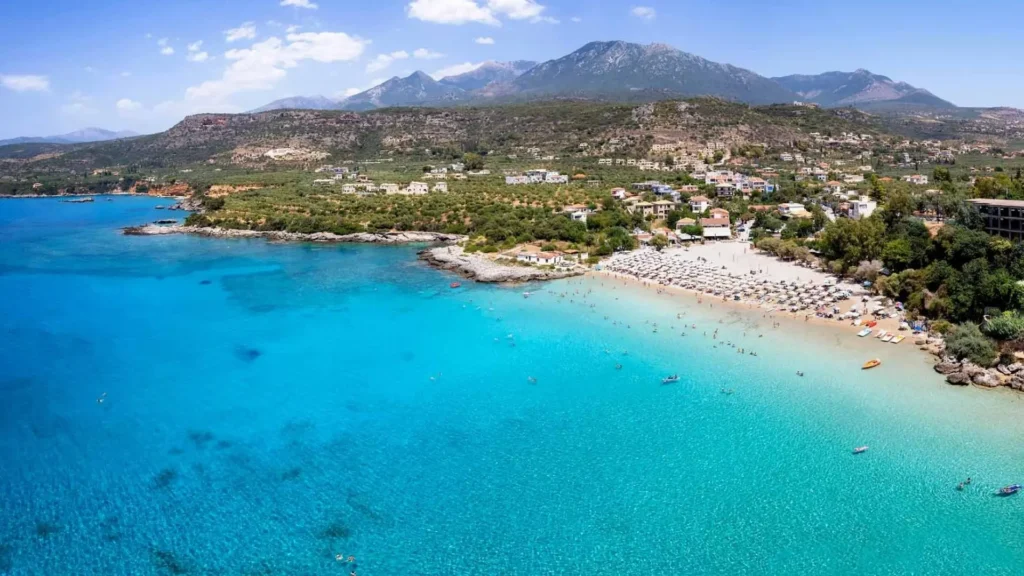 Aerial view of Kalogria Beach in Stoupa, Peloponnese with turquoise water and umbrellas along the sandy shore
