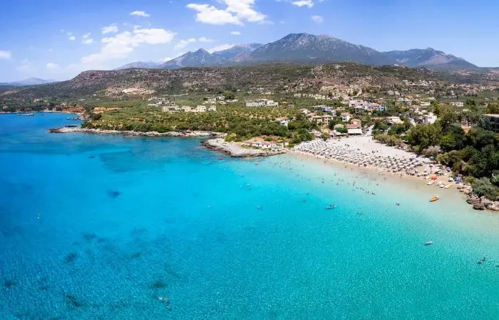 Aerial view of Kalogria Beach in Stoupa, Peloponnese with turquoise water and umbrellas along the sandy shore