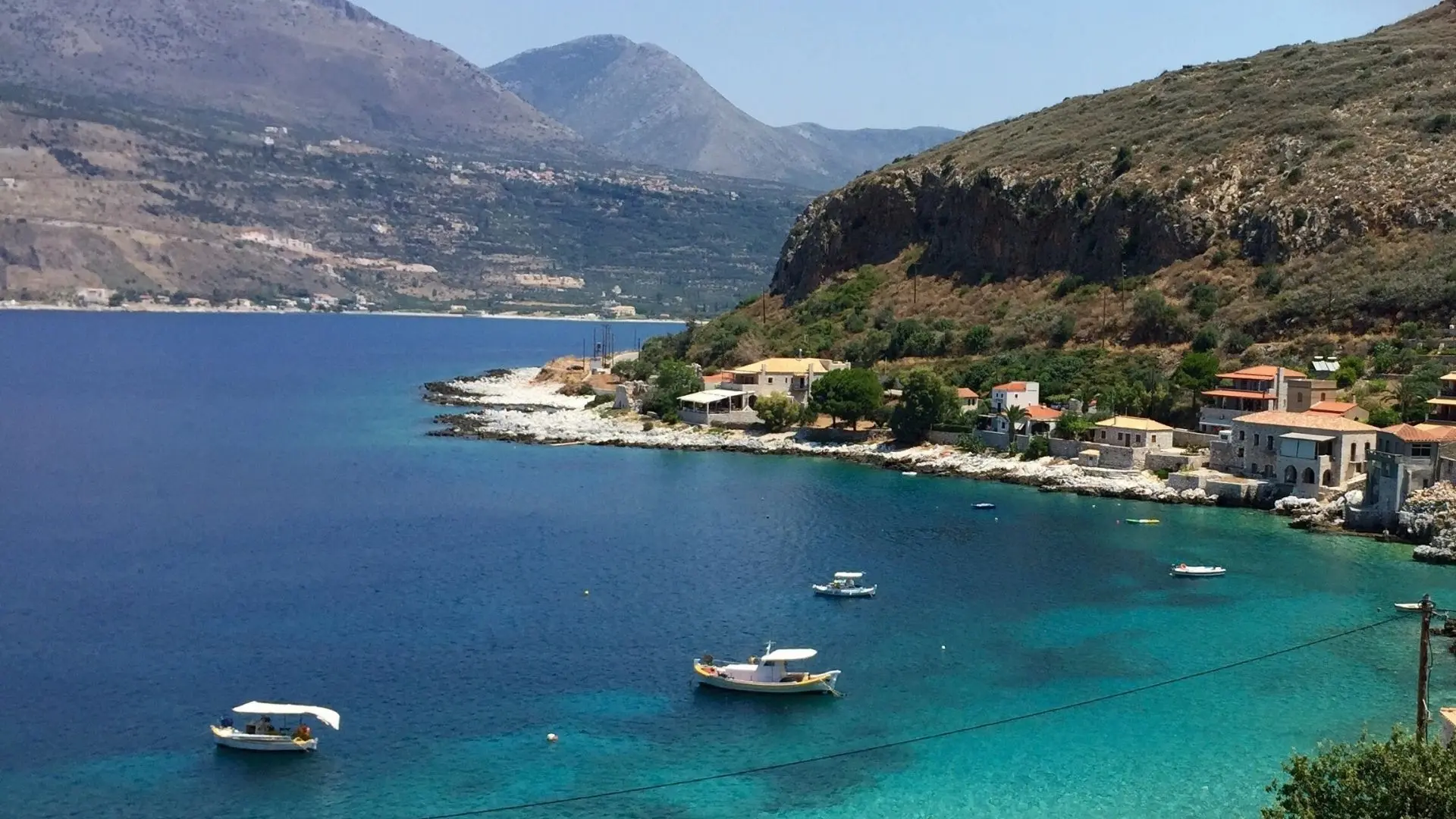 Colorful boats floating in the clear blue harbor of Limeni, Mani, Greece